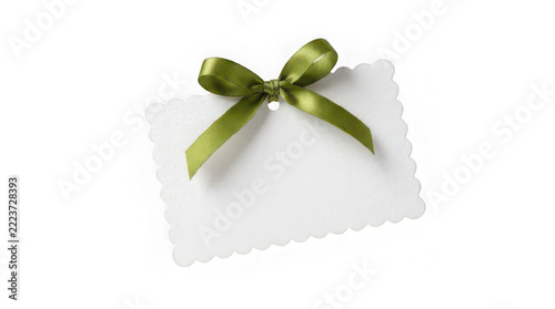 White scalloped gift tag with green ribbon bow isolated on
