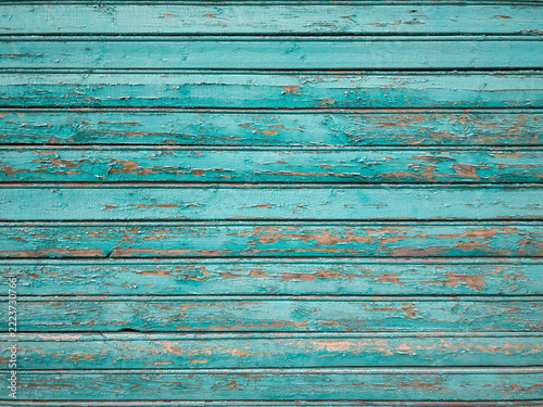 Texture from old wooden boards with peeling paint. Background painted in emerald color. Closeup.