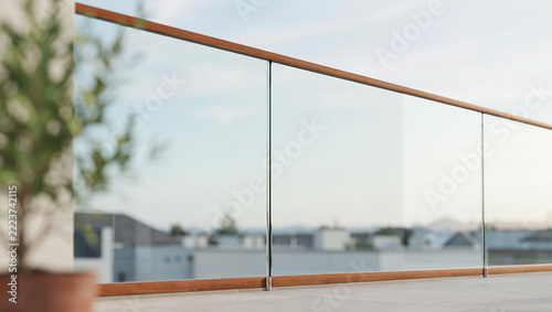 Modern glass balcony railing with wooden handrail overlooking