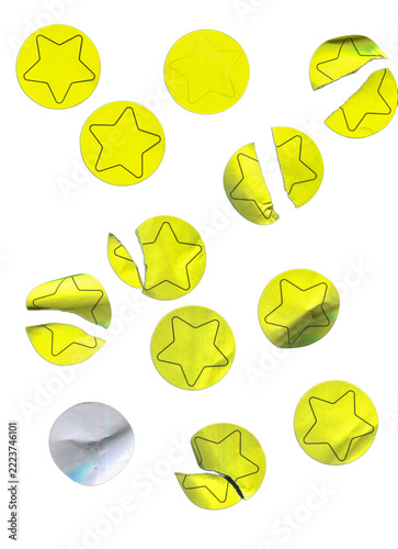 Yellow round star stickers, some peeled and folded, scattered on white background