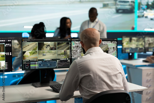 Traffic control, surveillance and camera feeds as operator checks road displays with coworkers nearby. Transport safety, urban mobility and monitoring support city traffic oversight in control room.