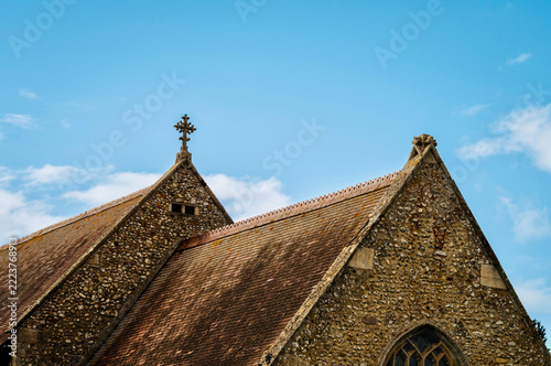 Historic Flint Stone Church Roof and Gothic Architecture Against Blue Sky