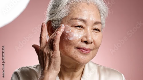Senior asian woman applying moisturizing cream on her face for daily