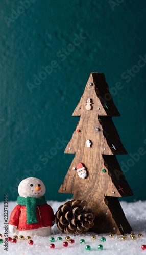 Carved Wooden Christmas Tree with Snowman Figurine and Pinecone on Artificial Snow Concept
