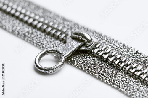 A metallic zipper with a pull tab is displayed against a plain white background