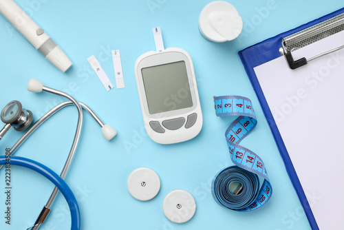 Glucose meter and strips with medical tools on blue