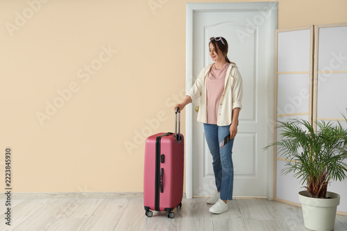 Travel preparation and vacation planning, young woman standing with suitcase and passport ready for departure in home interior