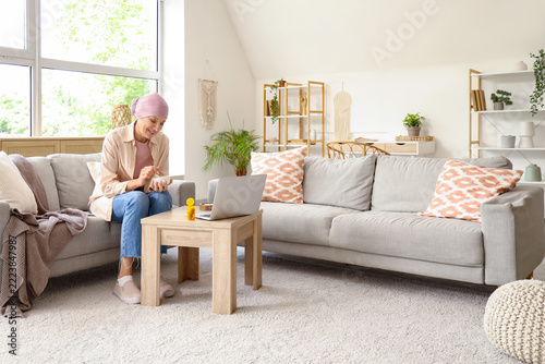 Cancer treatment and recovery, woman with headscarf taking medication while w...