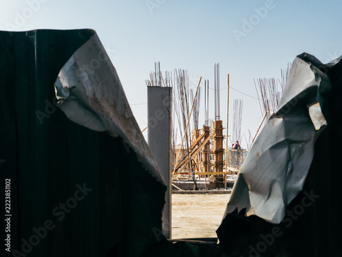 Construction Site Viewed Through a Damaged Perimeter Fence
