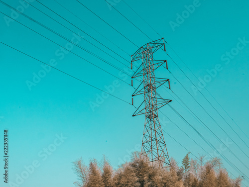 High Voltage Electricity Transmission Tower with Power Lines Against Turquoise Blue Sky
