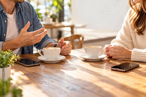 Two Adults Enjoying a Conversation Over Coffee with Smartphones Set Aside at a Cafe