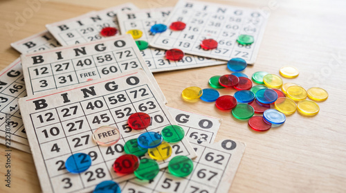 Classic Bingo cards and vibrant translucent markers on a wooden table, perfect for concepts of luck, social games, and senior activities.