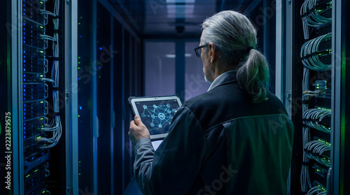 A person working on a tablet inside a high-tech server room or data center