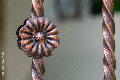 Twisted metal rods form elegant, rustic design. Copper-toned flower clasp adds decorative charm. Detailed craftsmanship highlights artisanal style. Ideal for garden fences or vintage home accents
