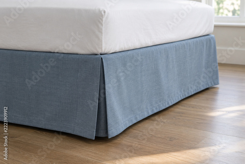 Blue Bed Skirt with a Corner Pleat Above a Wooden Floor