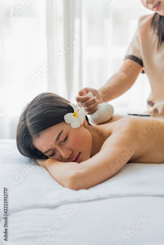 Asian woman laying on bed is being massaged in room