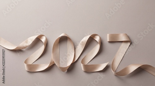 New Year 2027 ribbon typography concept photo. Sparkling beige textile ribbon shaped into numbers on neutral background. Elegant holiday greeting card background for seasonal events
