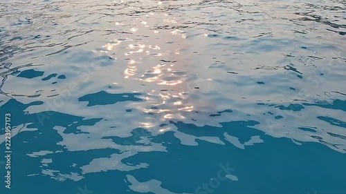 Gentle ripples move across turquoise pool water as warm sunset light sparkles on the surface