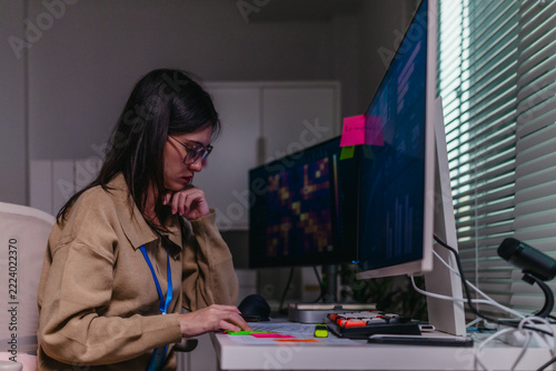Female data scientist analysing machine learning results on computer screen in office at night