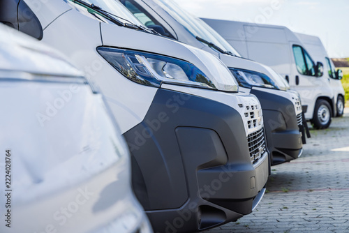 A row of white commercial vans parked for transport and logistics fleet operations work