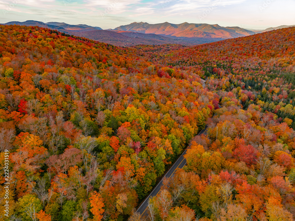 Fototapeta premium Aerial view of road in colorful autumn mountain forest during sunset