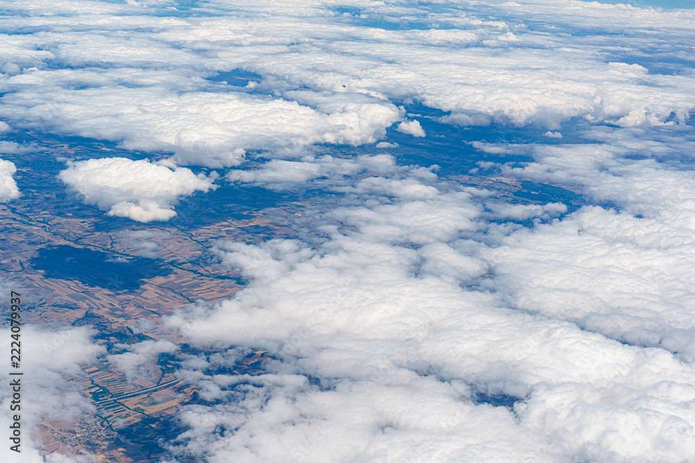 Fototapeta premium View of clouds from an airplane flying over farmland during daytime
