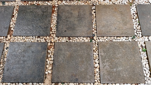 modern garden walkway designed with a structured, geometric layout. Large, square dark gray basalt or slate stepping stones are arranged in a grid pattern