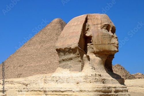 great sphinx of giza egypt. A close-up profile view of the Great Sphinx of Giza with the Great Pyramid rising prominently behind it. The weathered limestone face of the Sphinx is in sharp detail. 