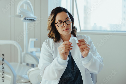 Examining the retainer, the dentist shows careful treatment planning in the clinic