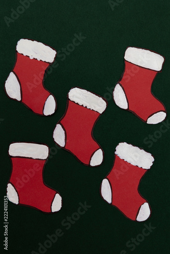 Red paper Christmas stockings on a dark green background, a festive concept and graphic resource for advertising campaigns, commercial designs, and seasonal creative projects