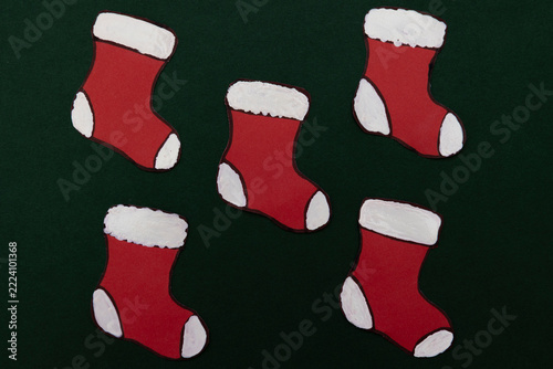 Red paper Christmas stockings on a dark green background, a festive seasonal concept and graphic resource for advertising, commercial designs, and creative projects