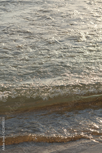Sandy beach and calm sea waves at sunset