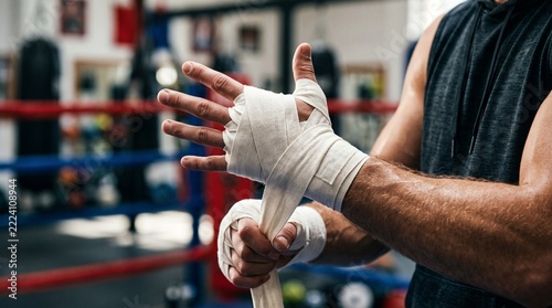 Professional boxer wrapping hands with tape in gym training session