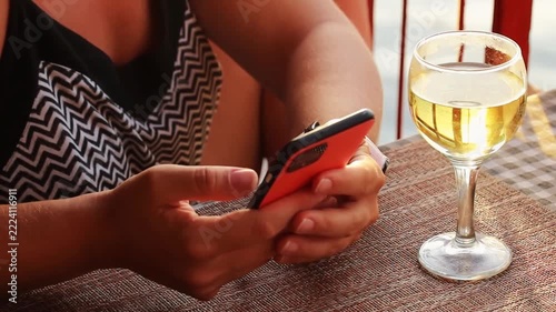 Woman hands with mobile phone and glass on wine close up at sunset