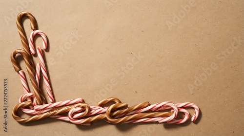 Striped brown and red candy canes arranged in an L-shape border on brown paper