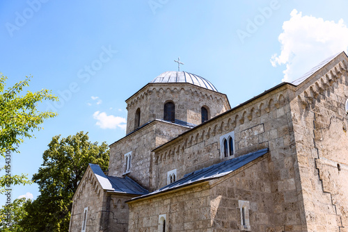 Gradac Monastery stone church framed by trees and summer sky, Serbia