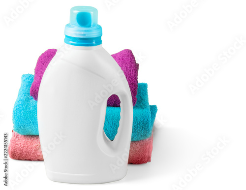 Bottle of laundry detergent next to stacked towels of various colors in a home setting