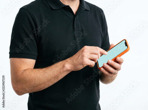 Man in black polo shirt holding smartphone isolated on white background
