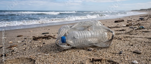 Plastic bottle and bag littering sandy beach showcasing marine pollution and environmental damage