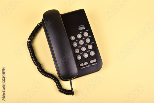 Retro black telephone yellow background. Top view. Concept of vintage technology, traditional telecommunication and minimalism.