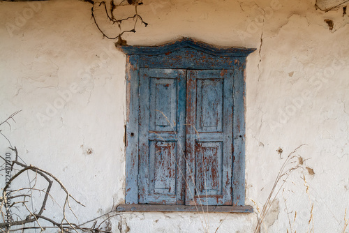 Close-up shot of old weathered blue wooden window shutters on rustic whitewashed clay wall