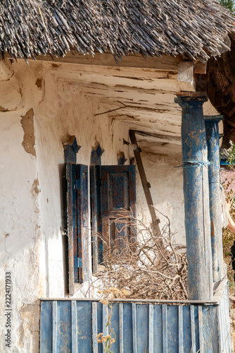 Architectural detail of porch columns and vintage blue shutters on old traditional thatched roof house