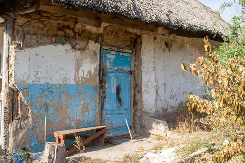 Weathered blue wooden door and peeling plaster on old traditional clay mud hut