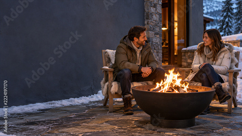 Man and woman sitting by an outdoor fire pit at a winter lodge