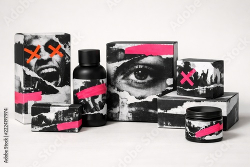 Punk grunge cosmetic packaging collection with black and white collage graphics, neon pink accents, and urban imagery arranged on white studio background for edgy branding, beauty marketing, and bold