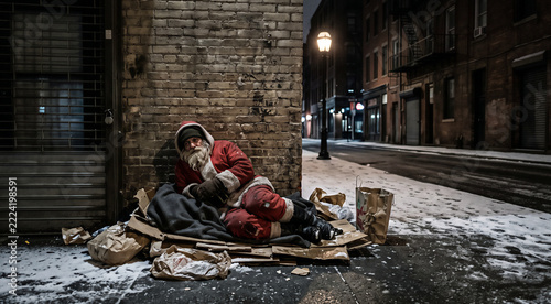 Homeless man dressed as Santa Claus sleeping on cardboard boxes in snowy city street at night, poverty during Christmas social inequality and despair concept