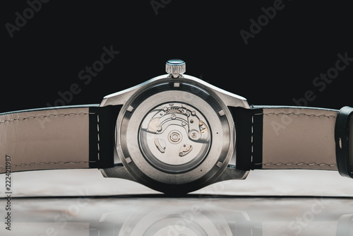 Swiss watch movement, back of analogue wristwatch showing mechanical cogs, leather strap