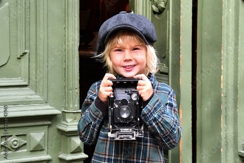 Boy in a flat cap holding an antique camera, vintage photography and historical style