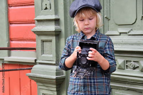Boy in a flat cap holding an antique camera, vintage photography and historical style