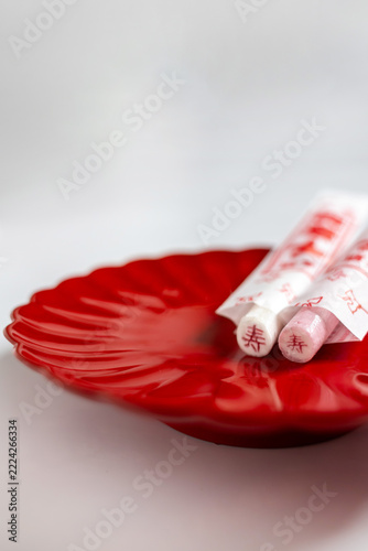 Red and white Japanese Chitose Ame candy on a red plate with copy space